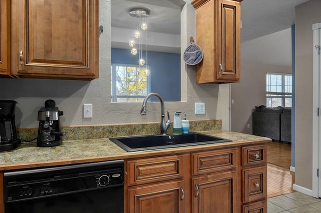 kitchen with sink, light hardwood / wood-style flooring, pendant lighting, and black dishwasher