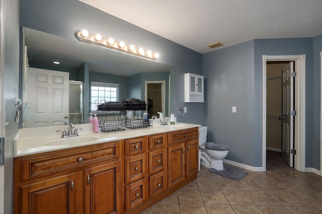 bathroom featuring tile patterned flooring, vanity, toilet, and a shower with door