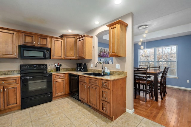 kitchen with sink, black appliances, and light hardwood / wood-style floors