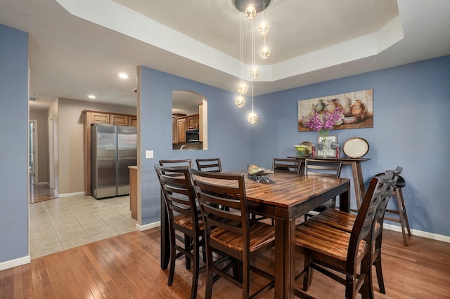 dining room featuring a tray ceiling and light hardwood / wood-style flooring