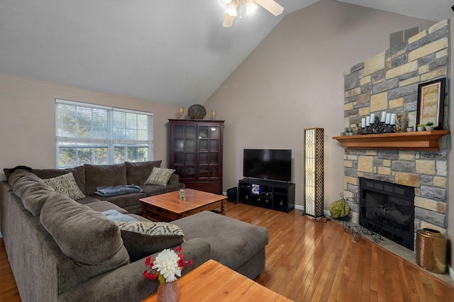 living room with a stone fireplace, ceiling fan, high vaulted ceiling, and hardwood / wood-style flooring