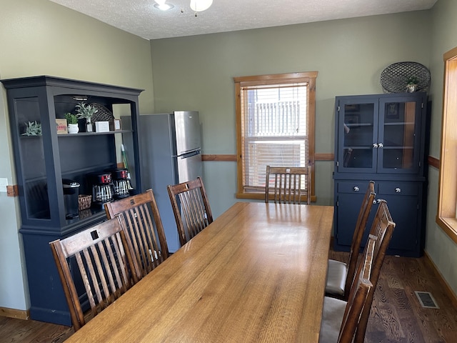 dining room with a textured ceiling and dark hardwood / wood-style floors