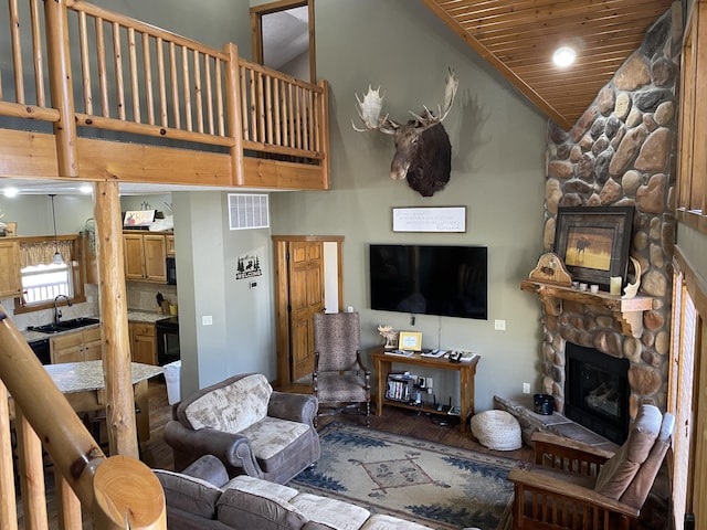 living room featuring wood ceiling, vaulted ceiling, sink, a fireplace, and hardwood / wood-style floors