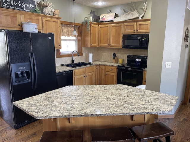 kitchen featuring a center island, sink, dark hardwood / wood-style floors, and black appliances