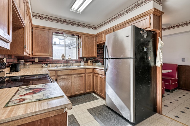 kitchen featuring tasteful backsplash, stainless steel fridge, and sink