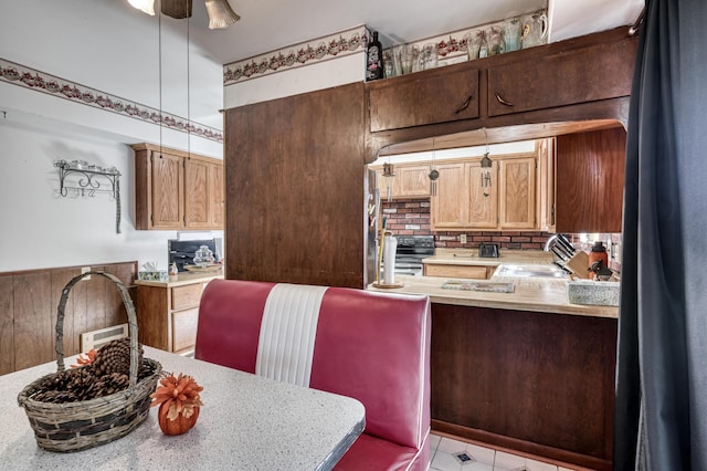 kitchen with kitchen peninsula, stainless steel fridge, tasteful backsplash, sink, and black electric range oven