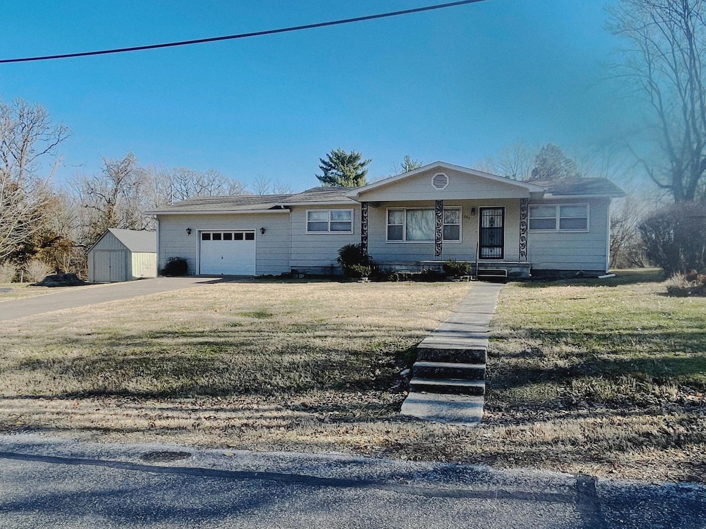 single story home with covered porch, an outbuilding, and a front yard