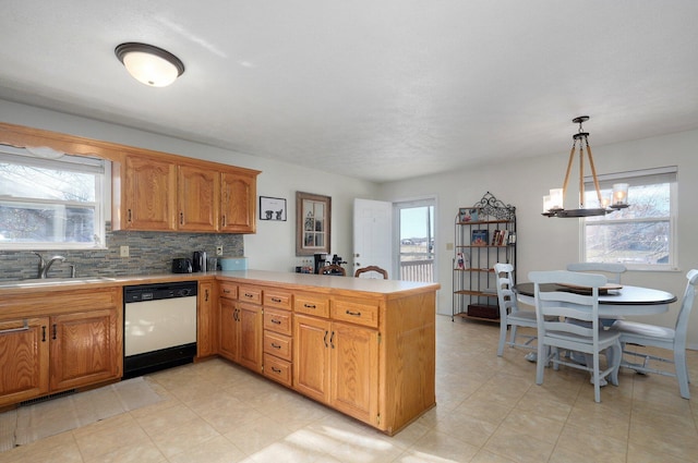 kitchen featuring kitchen peninsula, plenty of natural light, white dishwasher, and an inviting chandelier