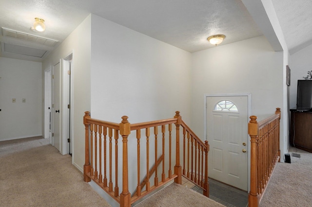 entrance foyer with a textured ceiling and light colored carpet