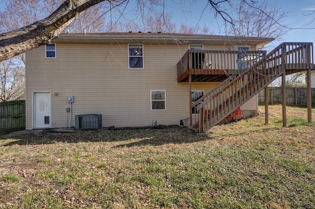 back of property with central AC, a wooden deck, and a lawn