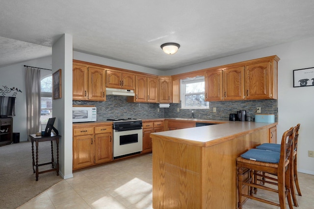 kitchen with a kitchen bar, kitchen peninsula, a textured ceiling, and range