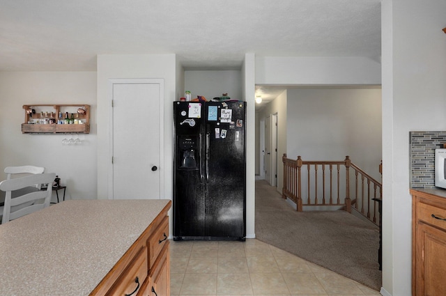 kitchen with black fridge with ice dispenser, a textured ceiling, and light colored carpet