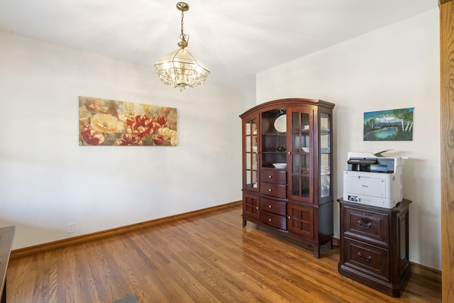 empty room with hardwood / wood-style floors and a notable chandelier