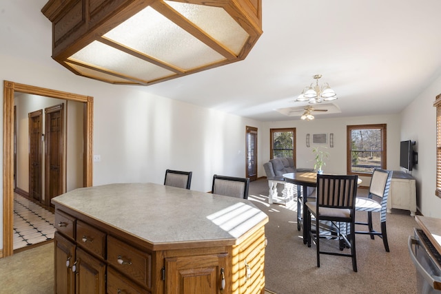 kitchen with ceiling fan with notable chandelier, light colored carpet, and a kitchen island