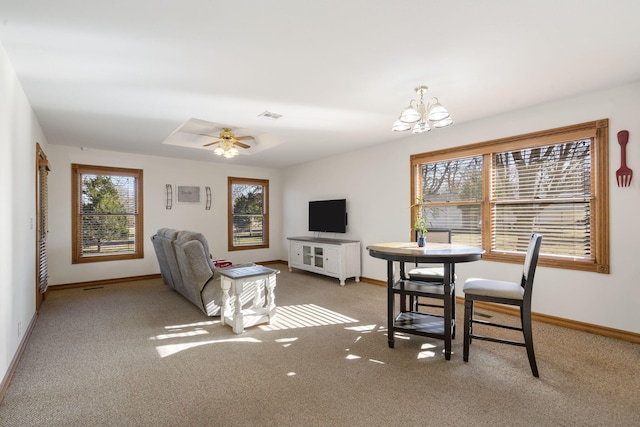 dining room with ceiling fan with notable chandelier, carpet floors, and a healthy amount of sunlight