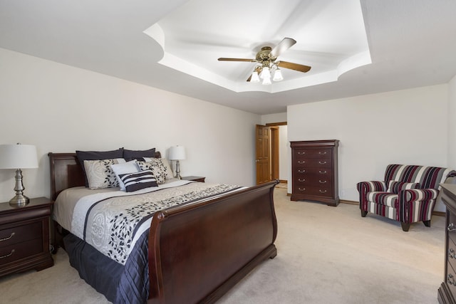 bedroom featuring ceiling fan, a raised ceiling, and light colored carpet