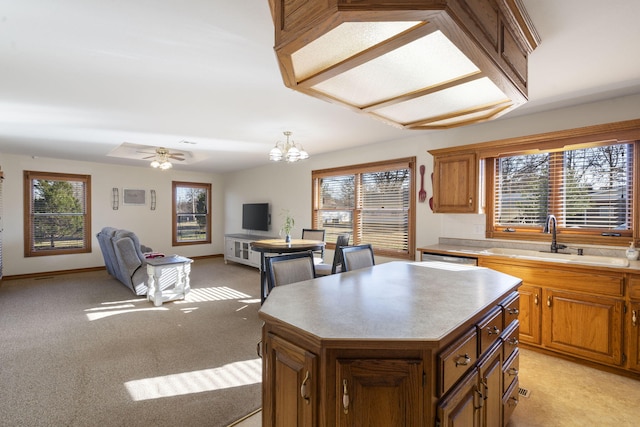 kitchen featuring sink, a center island, light colored carpet, decorative light fixtures, and ceiling fan with notable chandelier