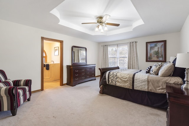 bedroom with ceiling fan, a raised ceiling, ensuite bathroom, and light carpet