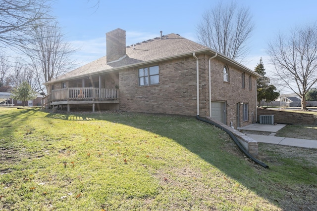 rear view of house featuring a lawn, a garage, central air condition unit, and a deck