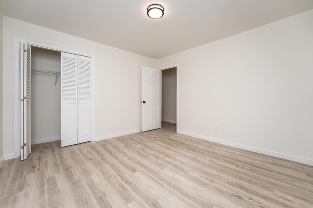 unfurnished bedroom featuring light wood-type flooring, baseboards, and a closet