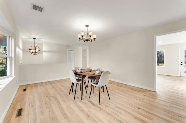 dining area with visible vents, baseboards, a chandelier, and light wood finished floors