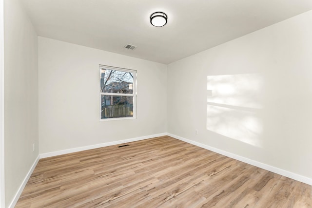 empty room featuring visible vents, light wood-type flooring, and baseboards