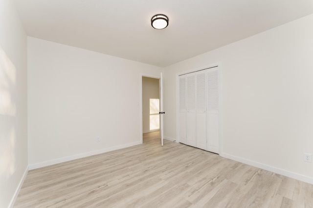 unfurnished bedroom with a closet, light wood-type flooring, and baseboards