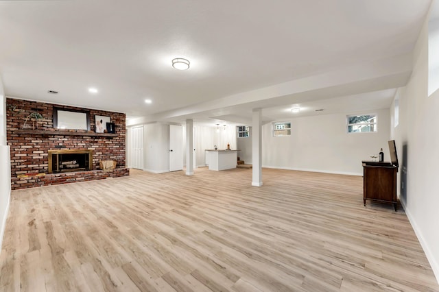 unfurnished living room featuring baseboards, a brick fireplace, and light wood-style flooring