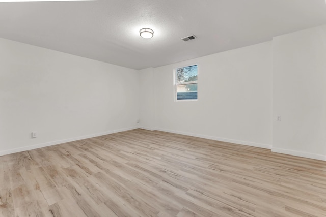 spare room with visible vents, light wood-style flooring, a textured ceiling, and baseboards