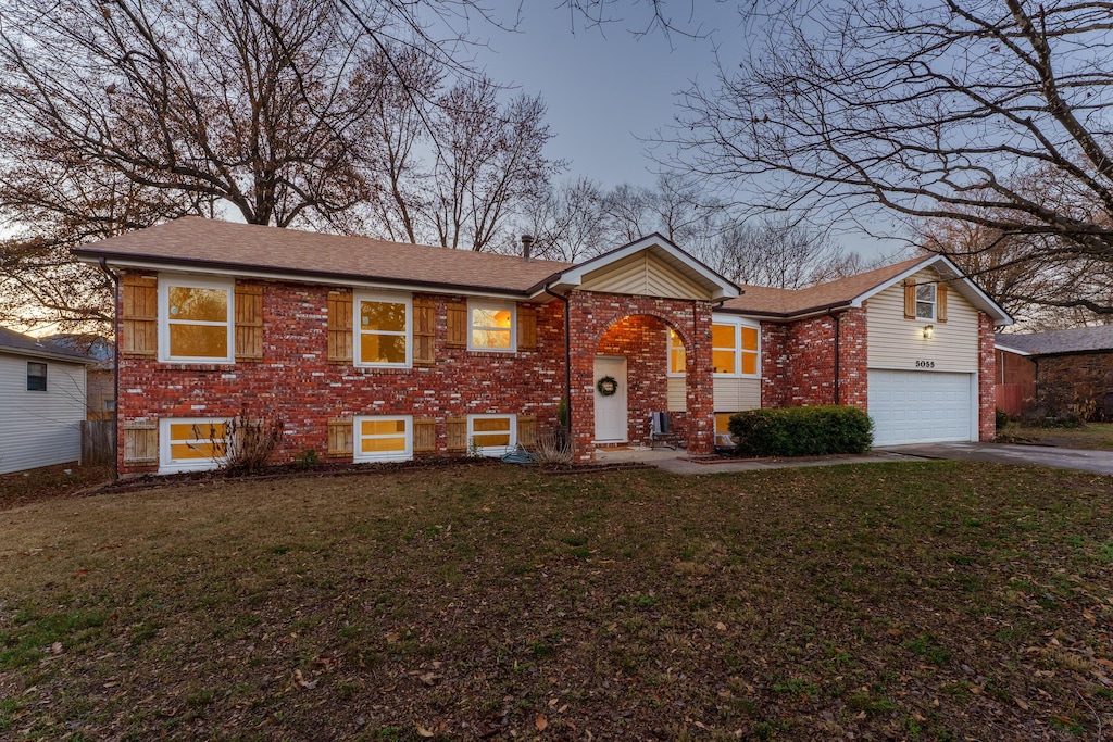 split foyer home with a front lawn, brick siding, and driveway