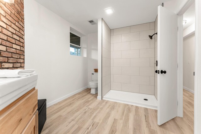 full bathroom featuring vanity, wood finished floors, visible vents, tiled shower, and toilet