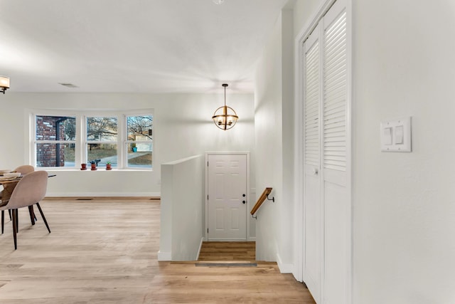 entrance foyer featuring light wood-type flooring, baseboards, visible vents, and a chandelier