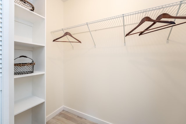 walk in closet with light wood-style floors