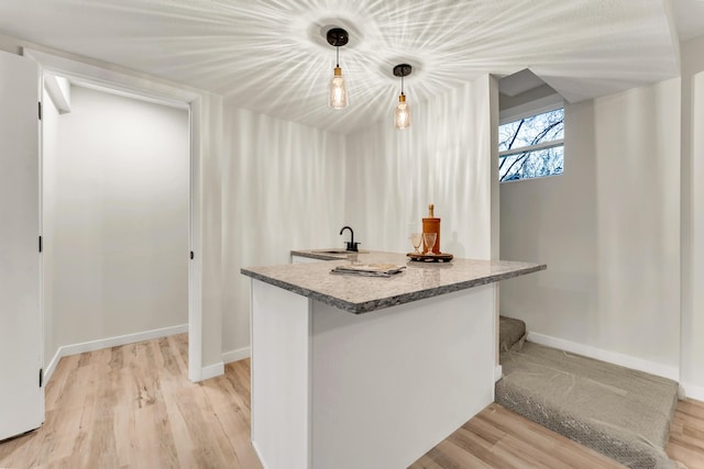 kitchen featuring a sink, baseboards, and light wood-style flooring