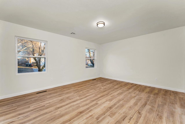 empty room featuring visible vents, baseboards, and light wood-style floors