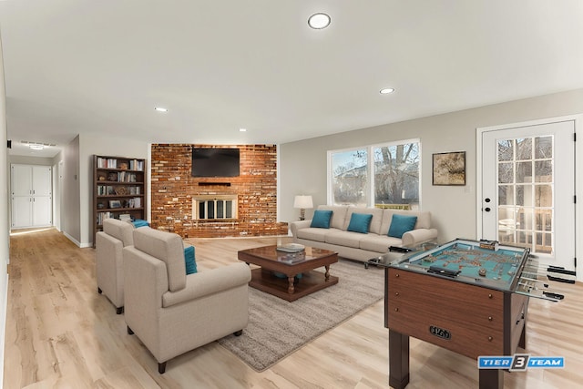 living area featuring recessed lighting, light wood-style floors, and a brick fireplace