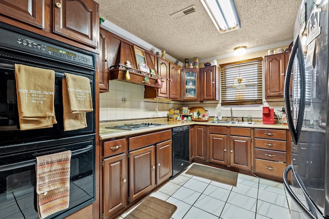 kitchen with sink, black appliances, custom range hood, a textured ceiling, and decorative backsplash