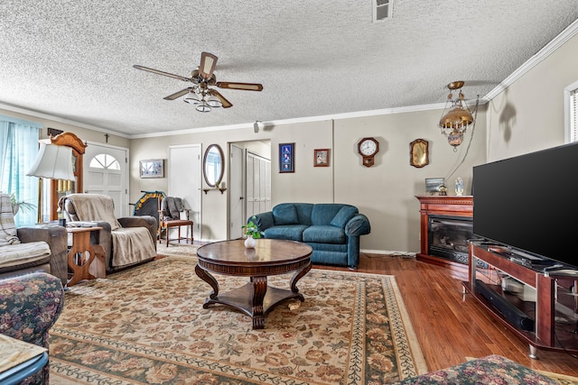 living room featuring crown molding, hardwood / wood-style floors, a textured ceiling, and ceiling fan