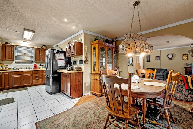 tiled dining room with ornamental molding, sink, and a textured ceiling