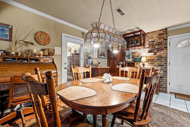 tiled dining space featuring ornamental molding, brick wall, and a textured ceiling