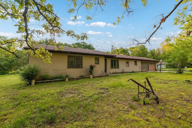 rear view of property featuring a garage and a lawn