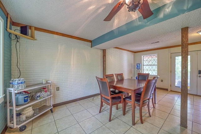 dining room featuring ceiling fan, light tile patterned floors, a textured ceiling, and brick wall