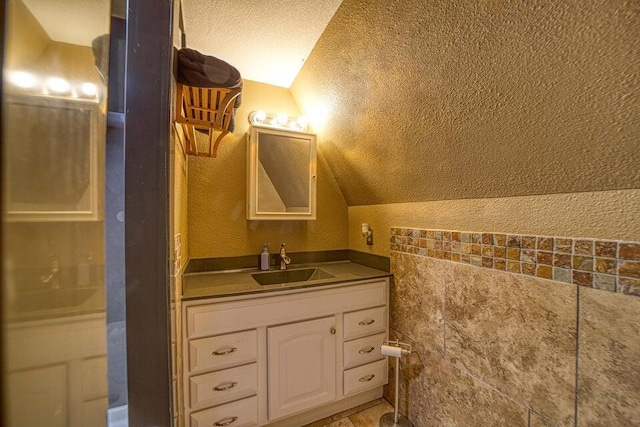 bathroom featuring vanity, lofted ceiling, and a textured ceiling