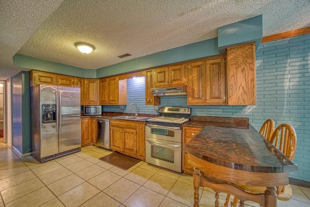 kitchen featuring decorative backsplash, appliances with stainless steel finishes, a textured ceiling, sink, and light tile patterned floors