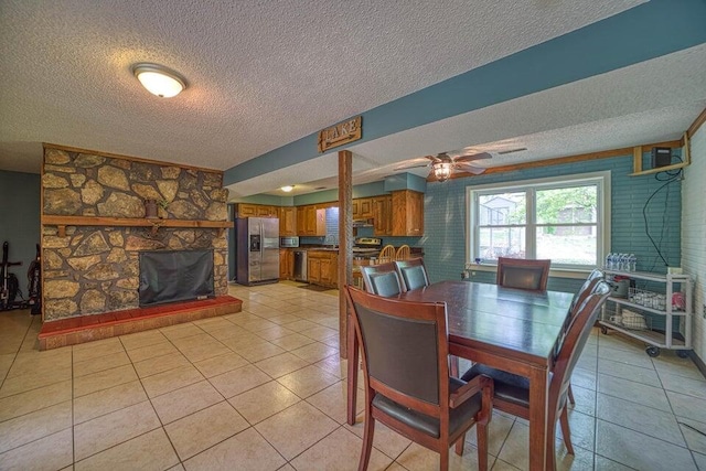 dining area featuring ceiling fan, light tile patterned flooring, and a textured ceiling