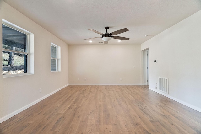 empty room featuring ceiling fan, light hardwood / wood-style flooring, and a textured ceiling