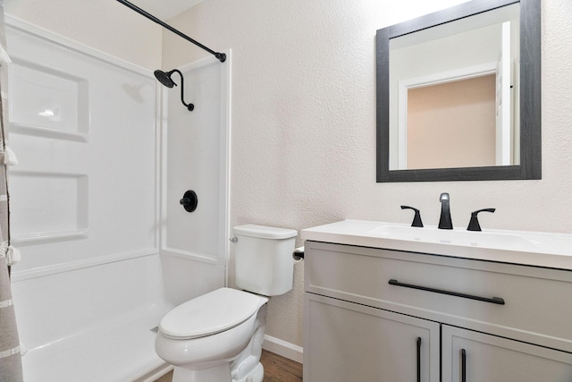 bathroom featuring wood-type flooring, vanity, toilet, and walk in shower