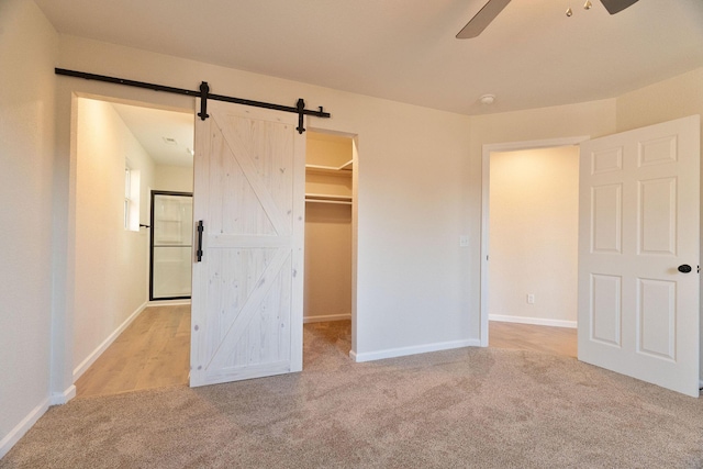 unfurnished bedroom with ceiling fan, a spacious closet, light carpet, and a closet