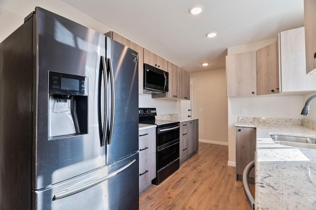 kitchen featuring sink, black appliances, light brown cabinets, and light wood-type flooring