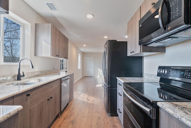 kitchen featuring appliances with stainless steel finishes, light wood-type flooring, plenty of natural light, and sink